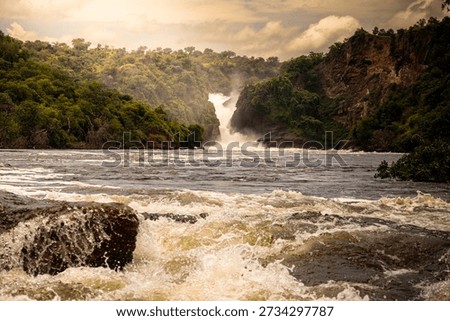 As the sun sets, the Nile crashes through Murchison Falls, glowing in warm evening light.