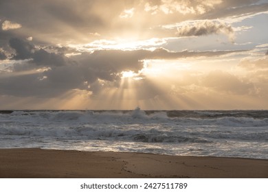 sun sets on a dramatic cloudy sky over the Mediterranean Sea horizon with a warm, golden glow. The sea's waves  magical tranquil seascape