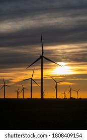 The sun sets on a field of wind turbines at a wind farm in Indiana, United States.
