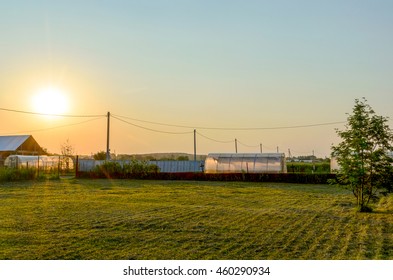 The sun sets over an empty area behind the fence.