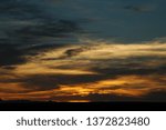 The sun sets over the flat line of the Texas horizon leaving orange, white and blue wisps of color.