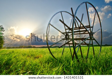 The sun sets over a grass field with machinery in Frisco, TX