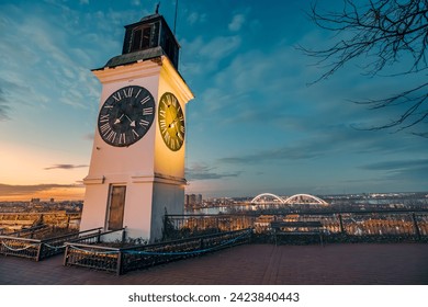 sun sets over Novi Sad, the iconic clock tower of Petrovaradin Fortress stands tall, offering a picturesque view of Serbian history and culture.