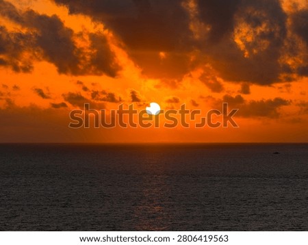 Sun sets over the open sea near Dhigurah island, Maldives. A tiny boat dots the water as clouds glow at their edges. Long focal length and balanced exposure guide the view.
