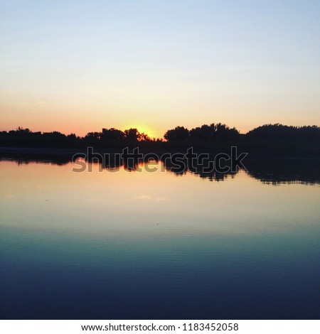 The  sun sets over a river as calm as it gets in Dinosaur Provincial Park, Alberta, Canada.