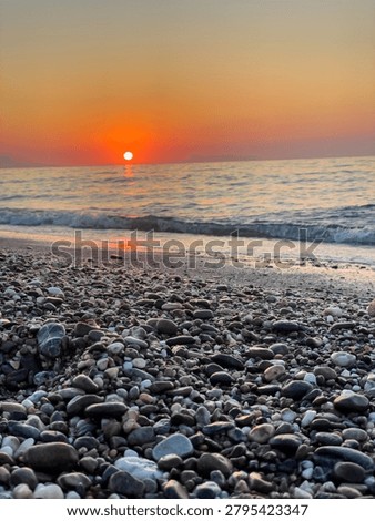 Sun sets over the sea as waves reach the shoreline at evening. Concept of tranquility, freedom and connection with nature.