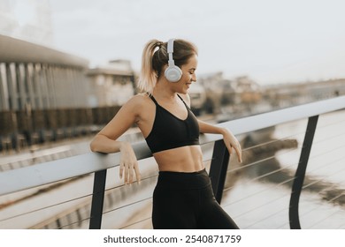 As the sun sets over the water, a young woman leans against a railing, savoring her favorite tunes through headphones, embracing tranquility and peace. - Powered by Shutterstock