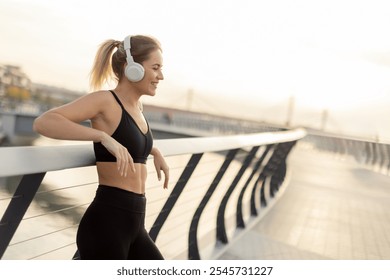 As the sun sets over the water, a young woman leans against a railing, savoring her favorite tunes through headphones, embracing tranquility and peace. - Powered by Shutterstock