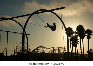 As The Sun Sets A Silhouetted Man Works Out On Gymnast Rings