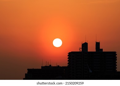 Sun Sets Through Orange Haze Over Silhouetted Buildings