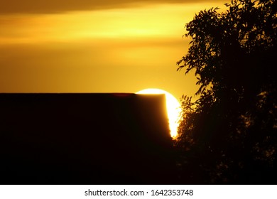 sun setting behind a building