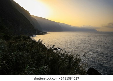 Sun setting behind the cliffs towering above Ponta Delgada, a small village on the north coast of Madeira island (Portugal) in the Atlantic Ocean