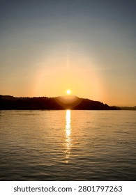Sun setting behind a mountain peak over the river water
