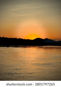 Sun setting behind a mountain peak over the river water