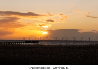Sun setting behind ocean wind power plant farm outside Skåne Sweden