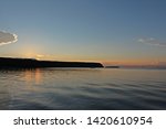 The sun setting behind a silhouetted tree line with the orange rays of light reflecting off the water in Eagle Harbor, Ephraim, Door County, Wisconsin, USA