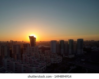 Sun is setting behind tower. Evening cityscape. Aerial view