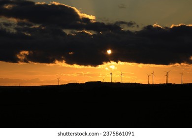 The sun is setting behind the wind park