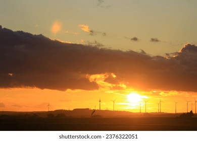 The sun is setting behind the wind park