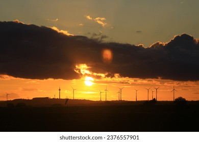 The sun is setting behind the wind park