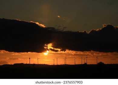 The sun is setting behind the wind park