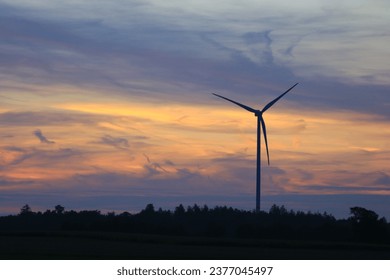 The sun is setting behind the wind park