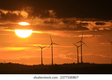 The sun is setting behind the wind park