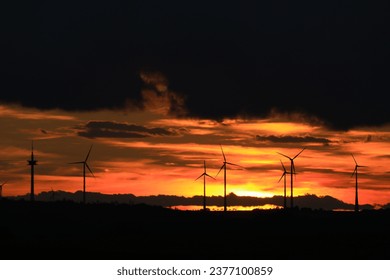 The sun is setting behind the wind park