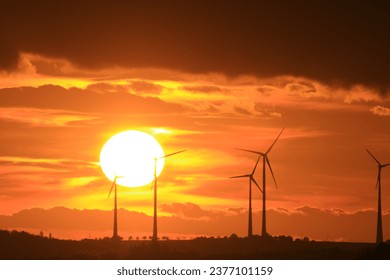 The sun is setting behind the wind park