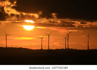 The sun is setting behind the wind park