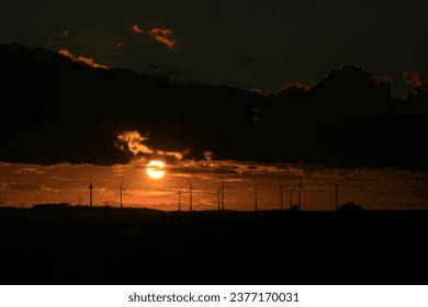 The sun is setting behind the wind park