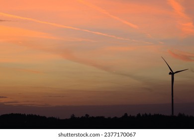 The sun is setting behind the wind park
