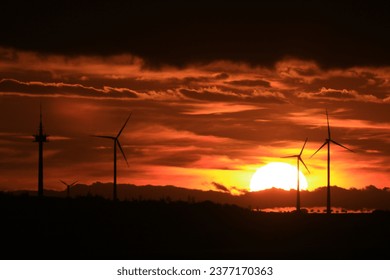 The sun is setting behind the wind park