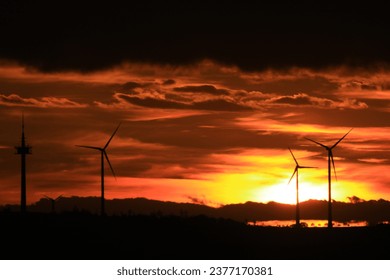 The sun is setting behind the wind park