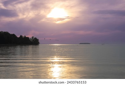 the sun i setting on a large lake and the birds are flying over the water