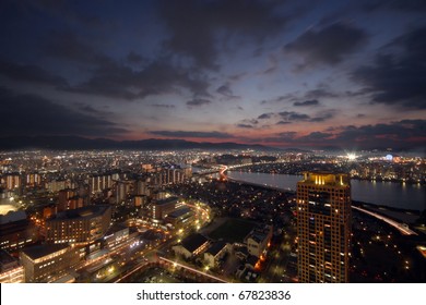 Sun setting over city with light up buildings in Japan - Powered by Shutterstock
