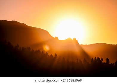 The sun is setting over a mountain range, casting a warm glow over the landscape. The sky is a mix of orange and pink hues, creating a serene and peaceful atmosphere