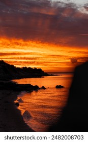 Sun setting over ocean beach with rocks in water