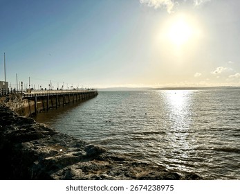 Sun setting over the ocean by the pier in Torquay, Torbay, Devon, UK