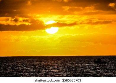 The sun is setting over the ocean, casting a warm glow on the water. A boat can be seen in the distance, adding to the peaceful atmosphere of the scene