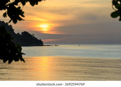 The sun is setting over the ocean, casting a warm glow on the water. The sky is filled with clouds, creating a serene and peaceful atmosphere. A boat can be seen in the distance