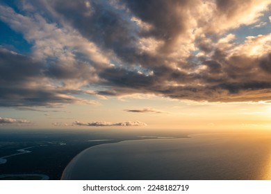  the sun is setting over the ocean and the clouds are very dark and cloudy in the sky above the water and land below the water is a large body of water with a boat in the foreground. .  - Powered by Shutterstock