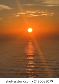 Sun setting over the ocean creating an orange sunset with water reflection. 