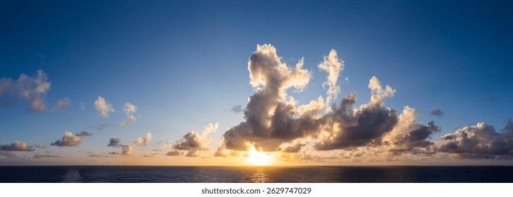 Sun setting over the ocean, highlighting dramatic clouds and creating a serene atmosphere.