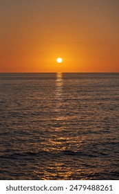 The sun setting over the ocean from a sandy beach