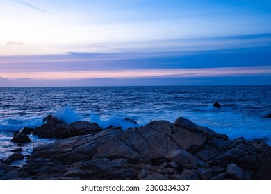 Sun  setting over the Pacific Ocean by a rocky coastline in California