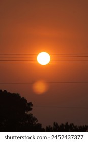 A sun setting over power lines