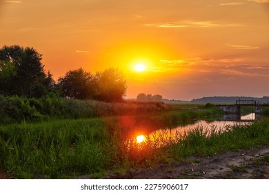 The sun is setting over a river and a bridge.