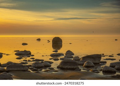 Sun is setting over the rocky pier to calm sea. Romantic view to stones in sea during sunset - Powered by Shutterstock