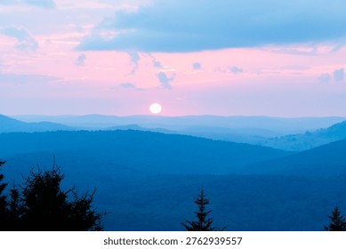 sun setting over rows and rows of blue ridge mountains in the distance and threatening to else over the horizon soon
